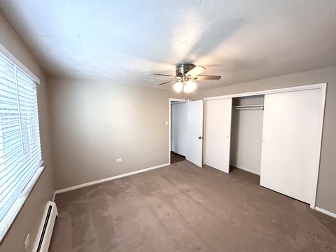 A room with a ceiling fan and a window with blinds.