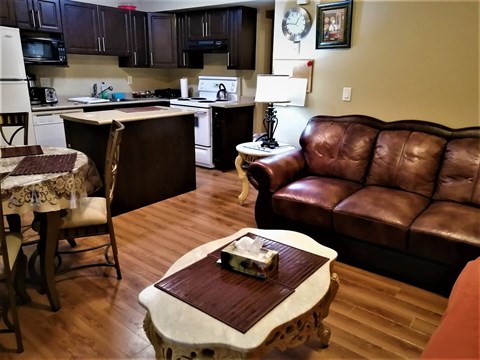 A brown leather couch sits in a kitchen with a table in front of it.