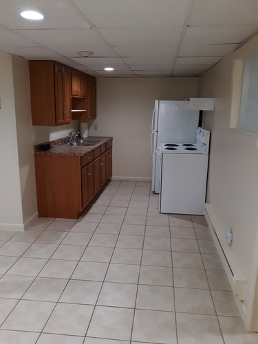 A kitchen with a white refrigerator and brown cabinets.