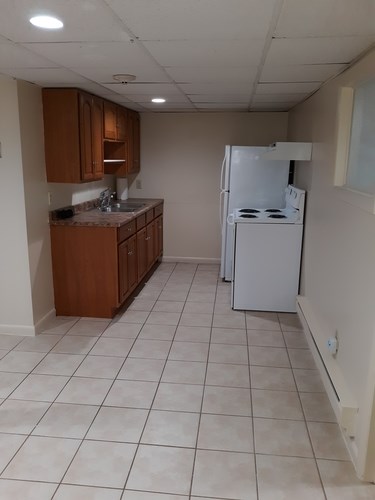 A kitchen with a white refrigerator and brown cabinets.