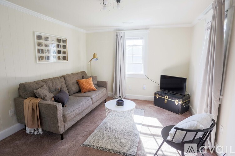 A living room with a grey couch, a white coffee table, and a black television.