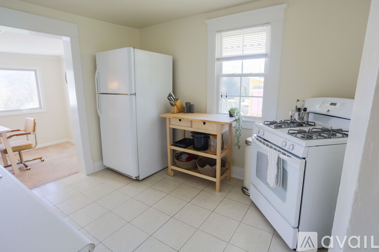 A kitchen with a white fridge, stove, and a table with a plant on it.