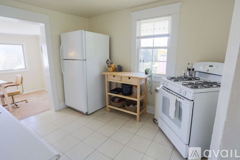 A kitchen with a white fridge, stove, and a table with a plant on it.