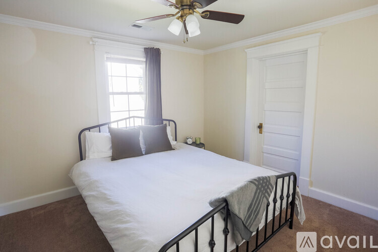 A bedroom with a bed, window, and a ceiling fan.