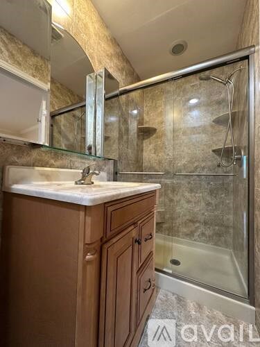 A bathroom with a sink, mirror, and shower.