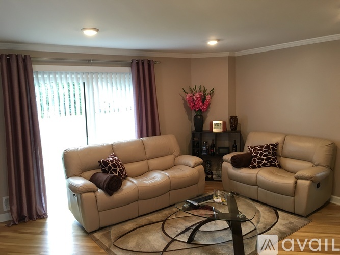 Two tan couches in a living room with a glass coffee table in between.