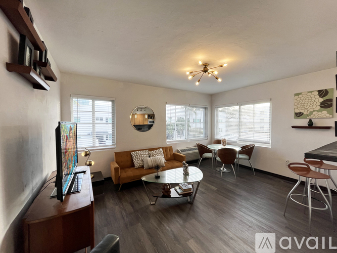 A living room with a brown couch, a television, and a chandelier.