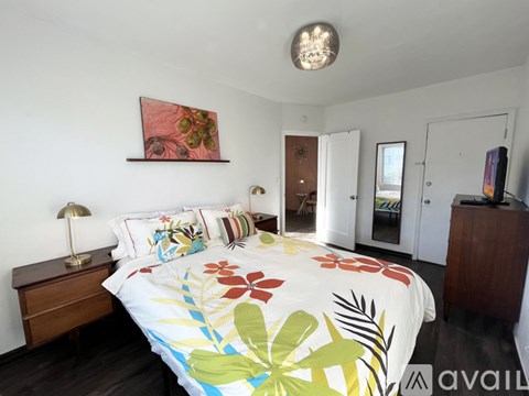 A bedroom with a large bed and a painting on the wall.