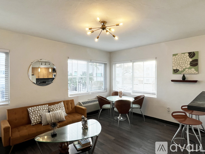 A living room with a brown couch, a glass table, and a ceiling fan.