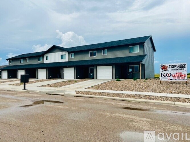 A building with a sign that says "Tiger Ridge Townhomes" in front of it.