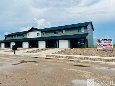 A building with a sign that says "Tiger Ridge Townhomes" in front of it.