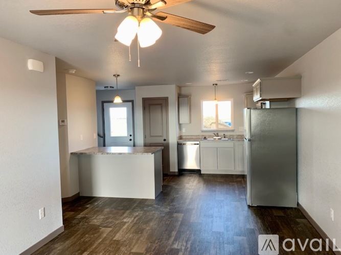 A kitchen with a refrigerator, sink, and cabinets.