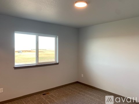 A room with a carpeted floor, a window, and a wall socket.