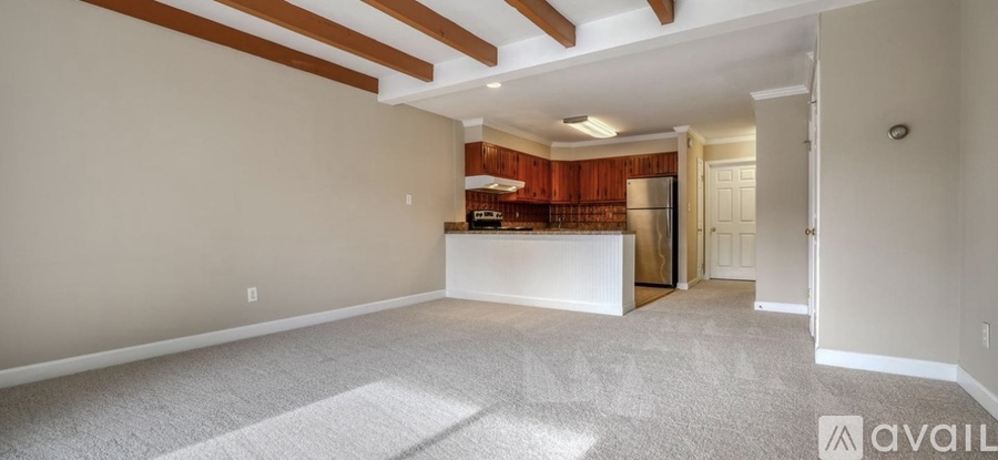 A spacious living room with a kitchen area in the background.