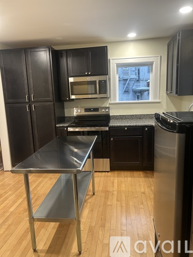 A kitchen with black cabinets and a stainless steel refrigerator.