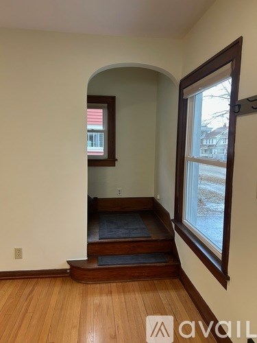 A room with wooden floors and a window with a view of a building outside.