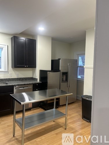 A kitchen with a stainless steel island and black cabinets.