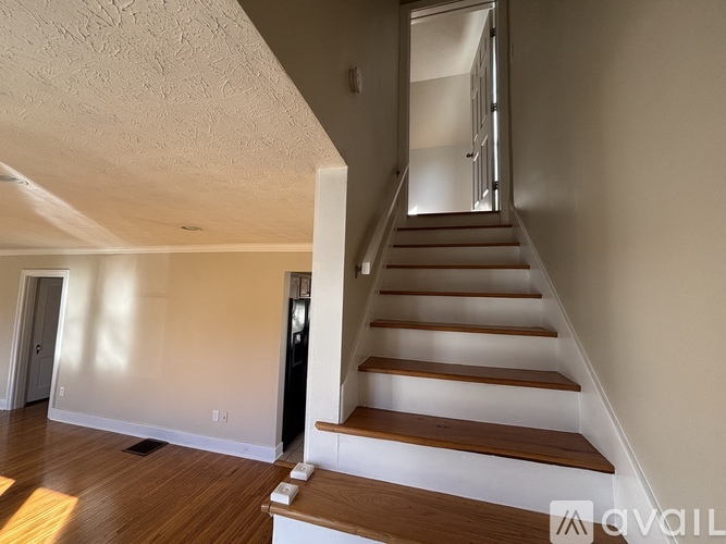 A staircase with wooden steps and white risers leads up to a doorway.