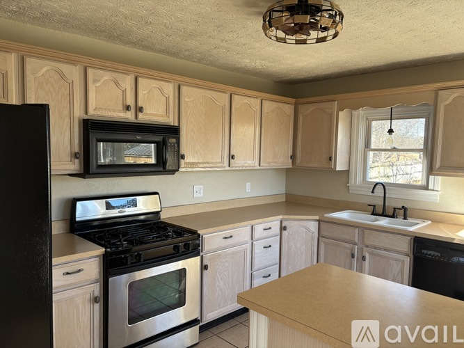 A kitchen with wooden cabinets and a black refrigerator.