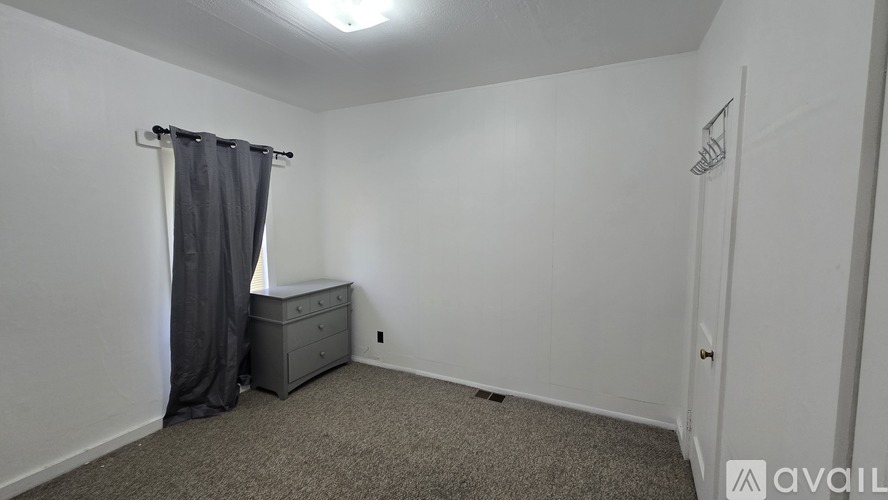 A small bedroom with a bed, dresser, and carpeted floor.