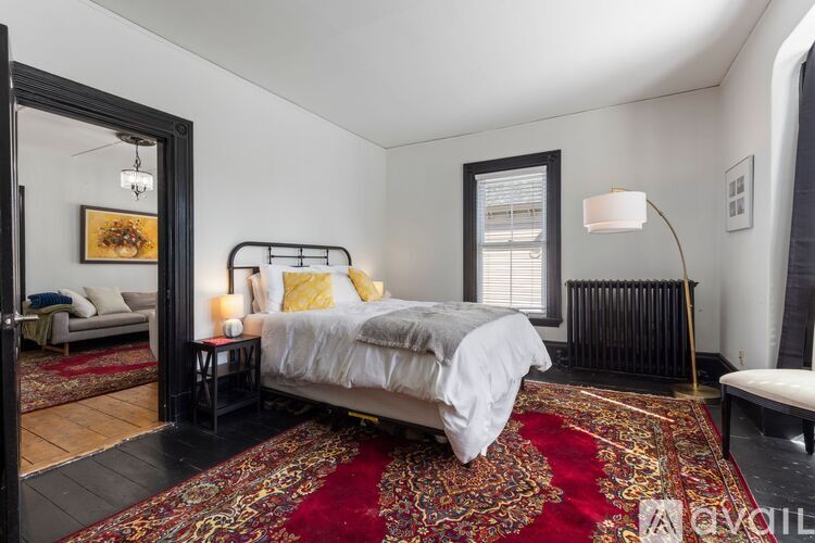A bedroom with a large bed and a red rug.