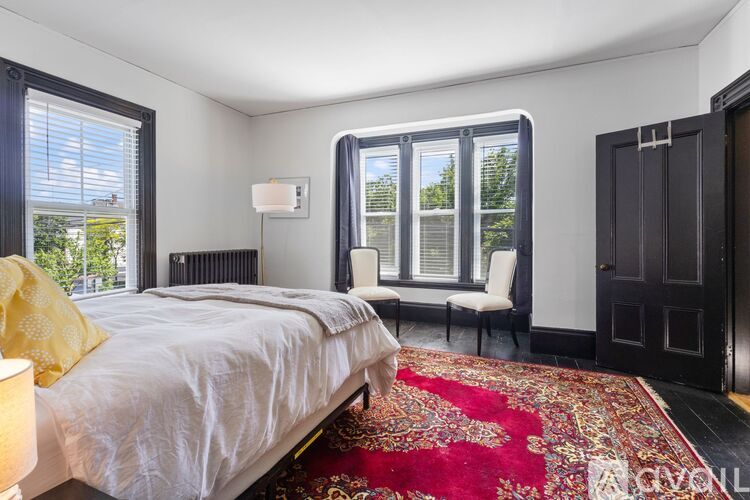 A bedroom with a large bed and a red rug.