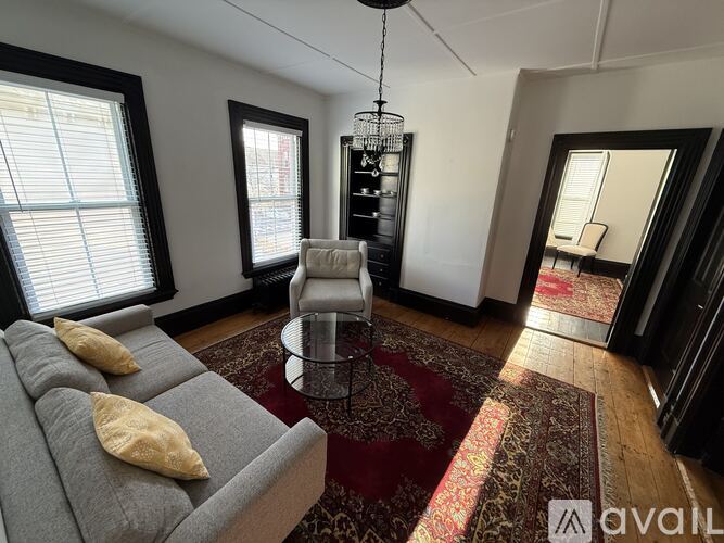 A living room with a grey sofa and a chandelier.