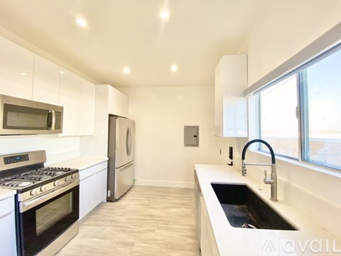 A modern kitchen with a stove, refrigerator, and a sink.
