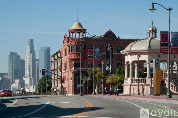 A city street with a red building and a tall building in the background.