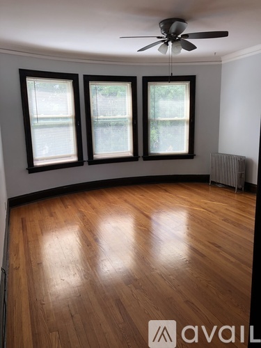 A room with wooden floors and three windows.