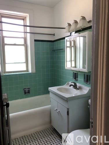 A bathroom with a white sink and green tiles.