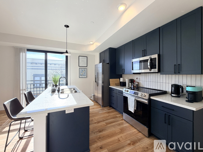 A modern kitchen with dark blue cabinets and a white island.