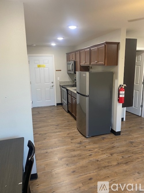 A kitchen area with a fridge, cabinets, and a dining table.