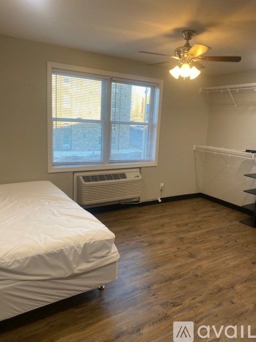 A room with a bed, a ceiling fan, and a window with blinds.