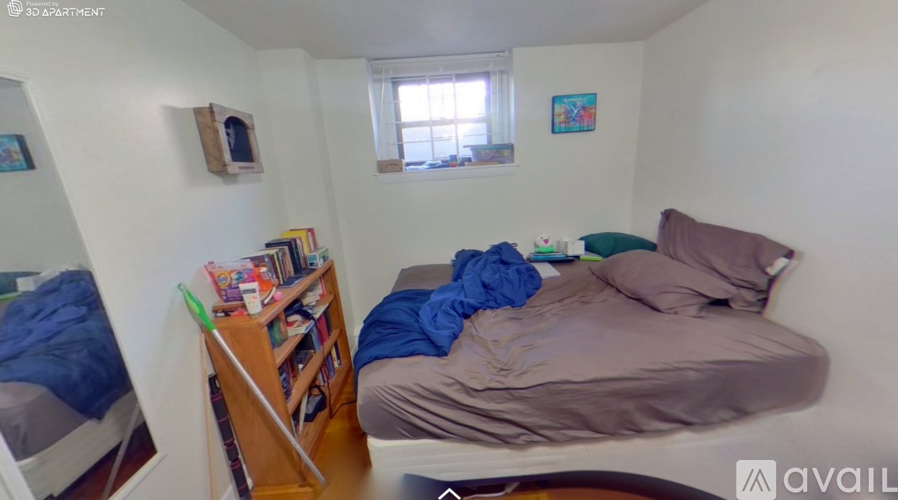 A bedroom with a bed, a bookshelf, and a window.