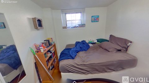 A bedroom with a bed, a bookshelf, and a window.