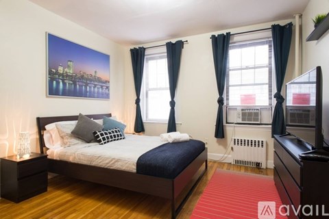 A bedroom with a large bed and a cityscape picture on the wall.