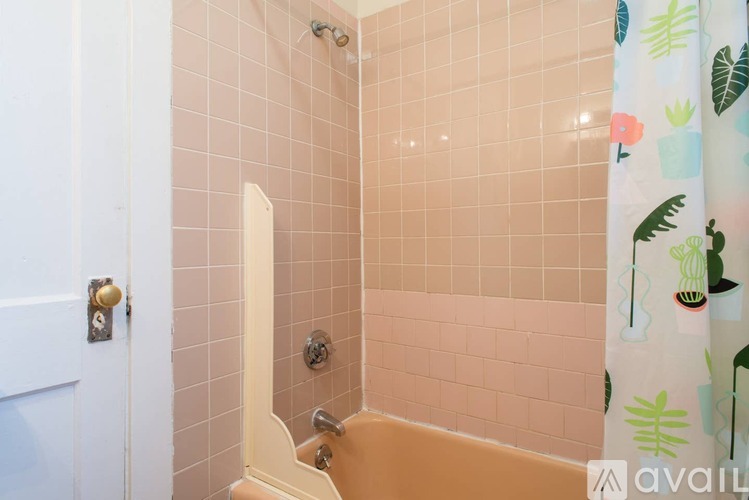 A bathroom with a pink tiled shower and a white door.