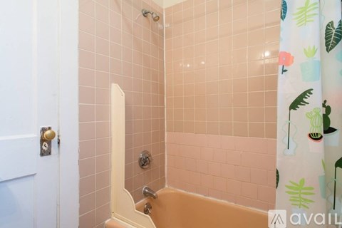 A bathroom with a pink tiled shower and a white door.