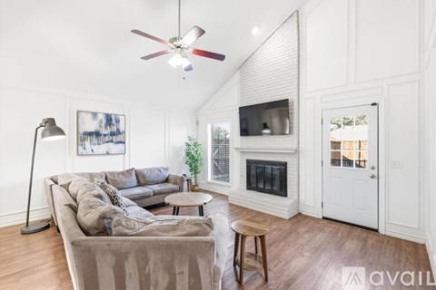 A living room with a grey couch and a white fireplace.