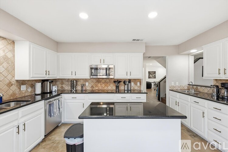 A kitchen with white cabinets and a black countertop.