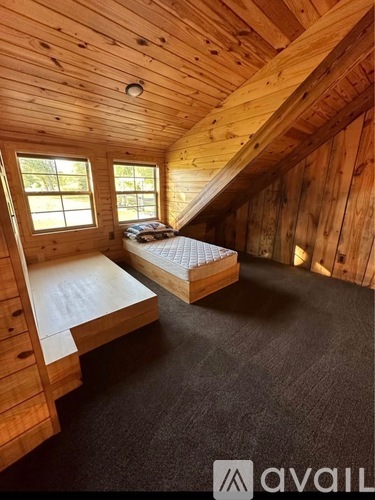 A bedroom with wooden walls and a bed with a mattress and pillows.