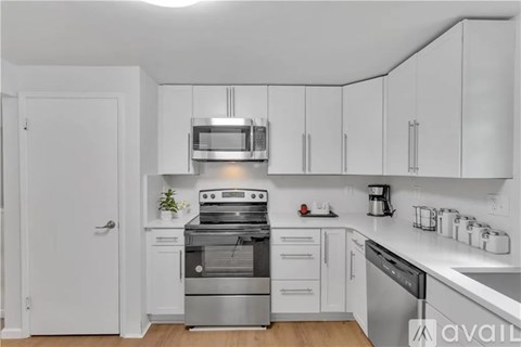 A modern kitchen with stainless steel appliances and white cabinetry.