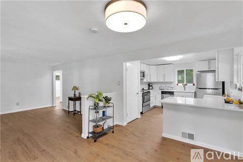 A kitchen with white appliances and wooden floors.