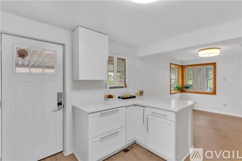 A kitchen with white cabinets and a window.