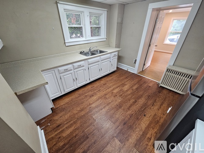 A kitchen with wooden floors and white cabinets.