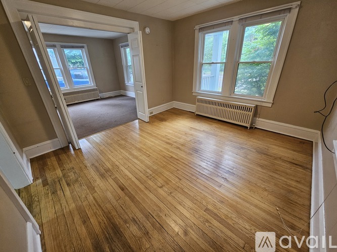 A room with wooden flooring and a window with a view of trees.