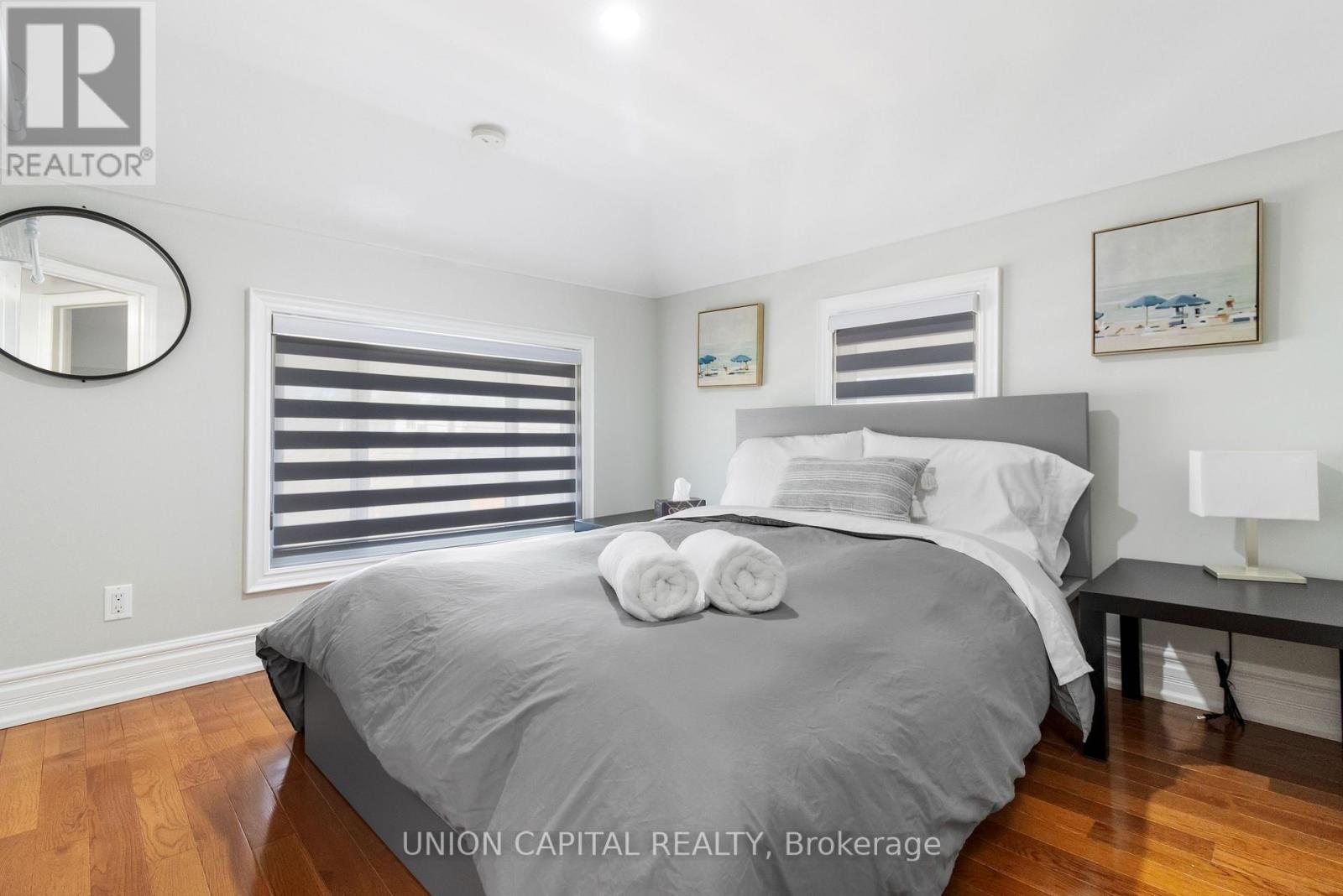 A bedroom with a large bed and a nightstand with a lamp.