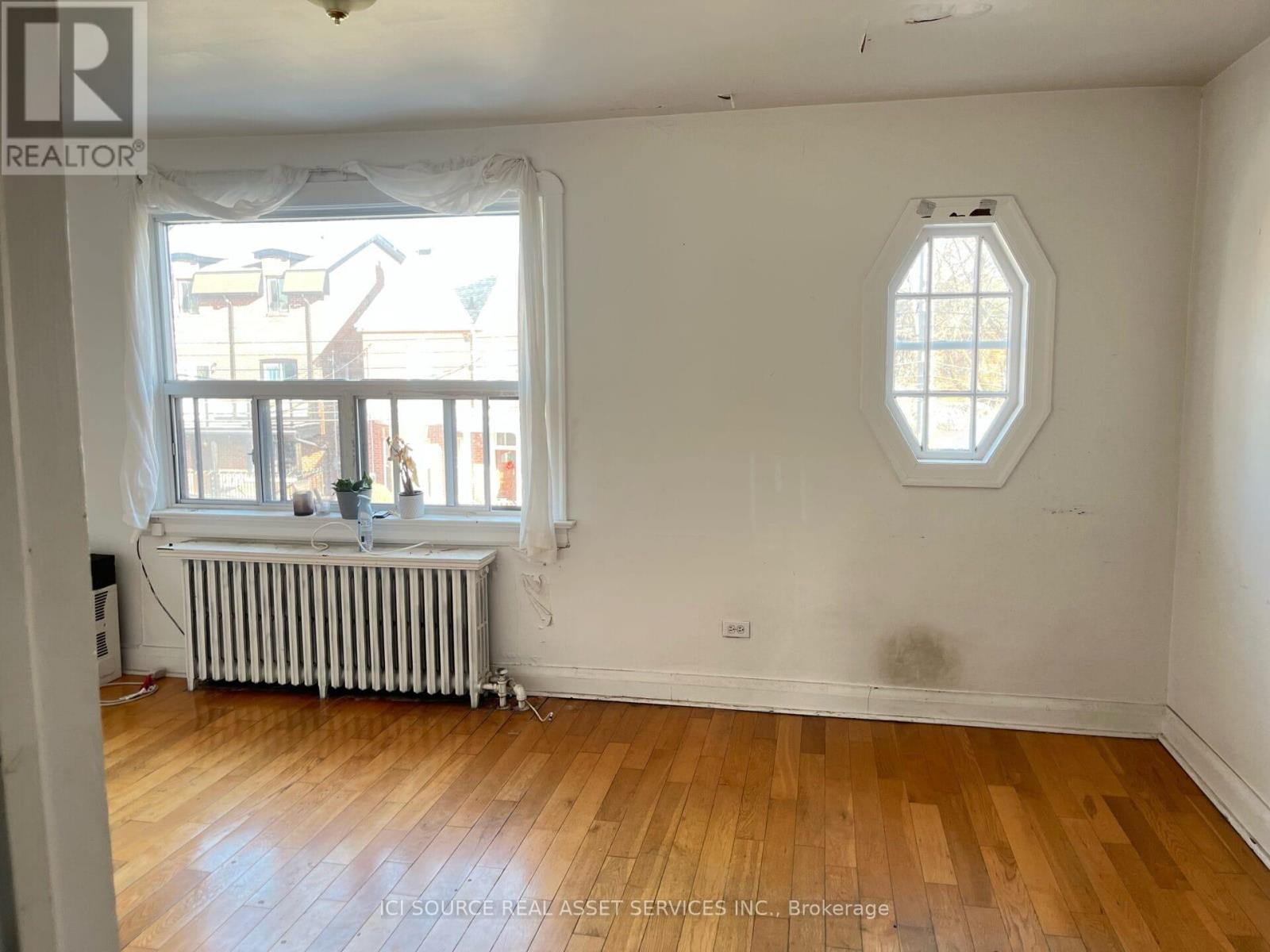 A room with a window and a wooden floor.