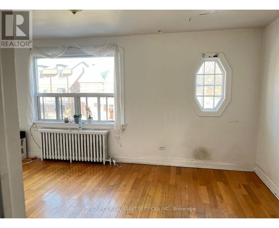 A room with a window and a wooden floor.
